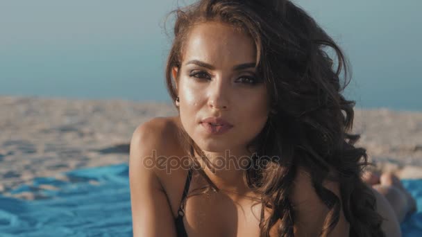 Primo piano di una bella giovane donna bruna che riposa sulla spiaggia. Ragazza prendere il sole sulla spiaggia — Video Stock