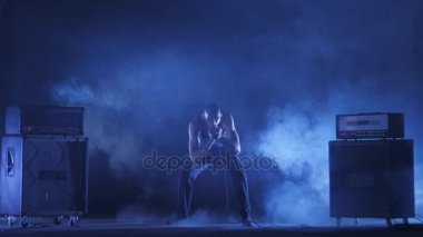 Erkek şarkıcı mikrofona doğru söylüyor. Şarkıcı sanatçı sahnede konser rock bant. Müzik video punk, ağır metal veya rock grubu