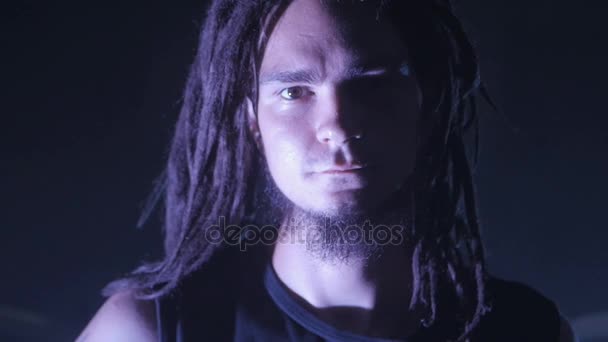 Close-up πορτρέτο ενός νεαρού άνδρα με dreadlocks και μια γενειάδα. Ένας μουσικός ή ένα μέλος του συγκροτήματος ροκ. — Αρχείο Βίντεο