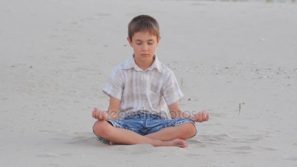 Chlapec, meditaci, seděl na písku na pláži v létě — Stock video