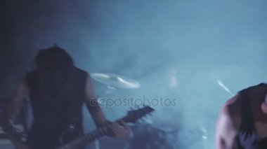 Konser rock grubu solisti, gitarist ve baterist ile sahnede performans. Müzik video punk, ağır metal veya rock grubu.