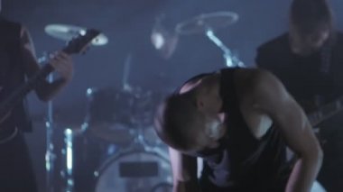 Konser rock grubu solisti, gitarist ve baterist ile sahnede performans. Müzik video punk, ağır metal veya rock grubu.