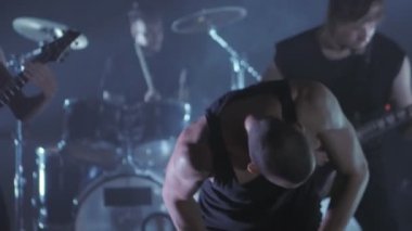 Konser rock grubu solisti, gitarist ve baterist ile sahnede performans. Müzik video punk, ağır metal veya rock grubu.