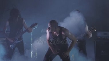 Konser rock grubu solisti, gitarist ve baterist ile sahnede performans. Müzik video punk, ağır metal veya rock grubu.