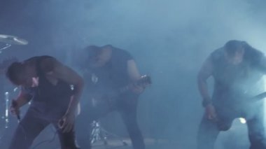 Konser rock grubu solisti, gitarist ve baterist ile sahnede performans. Müzik video punk, ağır metal veya rock grubu.