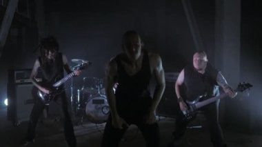 Konser rock grubu solisti, gitarist ve baterist ile sahnede performans. Müzik video punk, ağır metal veya rock grubu.