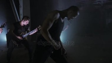 Konser rock grubu solisti, gitarist ve baterist ile sahnede performans. Müzik video punk, ağır metal veya rock grubu.