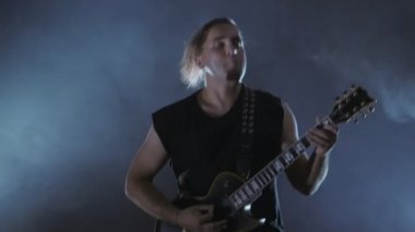 Vahşi erkek rocker elektrik gitar çalıyor. Müzik video punk, ağır metal veya rock grubu.