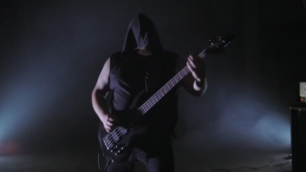 Un homme brutal dans un capot jouant de la guitare basse. Clip punk, heavy metal ou groupe rock . — Video