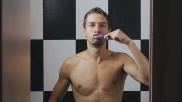 Ung man borsta tänderna i badrummet — Stockvideo