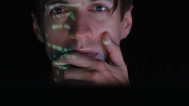 Oda karanlık ofis onun yüzünde yeşil kod karakterlerini yansıtan iken bir bilgisayarda çalışan adam programcı hacker.