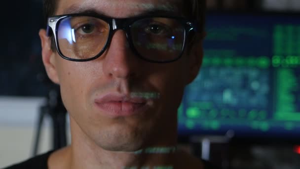 Portrait of Man programmer hacker with green code characters reflect on his face with a computer screen on the background — Stock Video