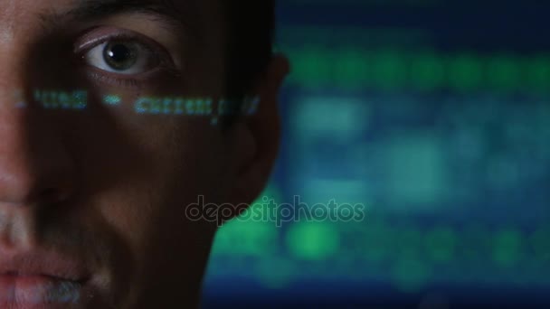 Retrato del hombre programador hacker con caracteres de código verde reflejan en su cara con una pantalla de ordenador en el fondo — Vídeos de Stock