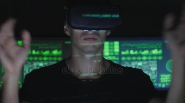 Erkek hacker programcı bir sanal gerçeklik kask yüzünde yeşil kod karakterlerini yansıtan iken programlama için kullanır. Bu geleceğin teknolojileri.