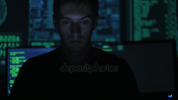 Portrait of a young programmer working at a computer in the data center filled with display screens — Stock Video