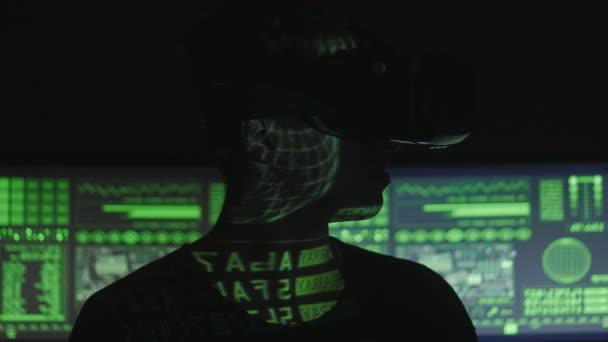 Male hacker programmer uses a virtual reality helmet for programming while green code characters reflect on his face. IT Technologies of the Future. — Stock Video