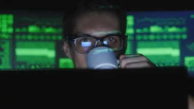 Hacker programcı bardaklarda bilgisayarda çalışarak ve Siber Güvenlik Merkezi'nde kahve içme göstermek perde ile dolu.