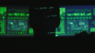 Yeşil kod karakterlerini iken bir dizüstü açılış hacker programcı programcı silüeti yansıtmak göstermek perde ile dolu siber güvenlik Merkezi'ndeki yüzünde.