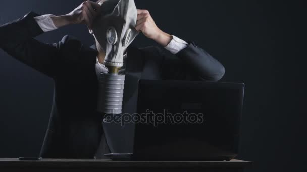 Empresario con máscara de gas trabajando en la computadora portátil en la oficina oscura — Vídeos de Stock