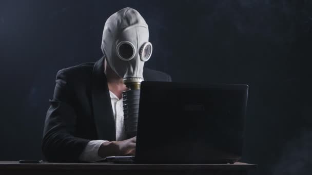 Podnikatel na sobě plynovou masku, pracovat na notebooku v tmavé kanceláři — Stock video