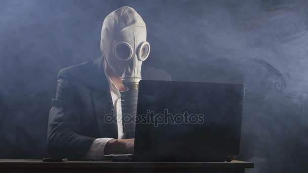 Empresario con máscara de gas trabajando en la computadora portátil en la oficina oscura — Vídeos de Stock