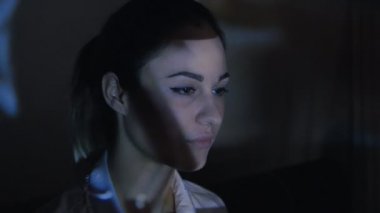 Yakın çekim bir video ya da Tv veya bilgisayar monitörü film izlerken genç bir kadın. Yansıma yüzünde