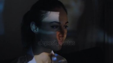 Yakın çekim bir video ya da Tv veya bilgisayar monitörü film izlerken genç bir kadın. Yansıma yüzünde