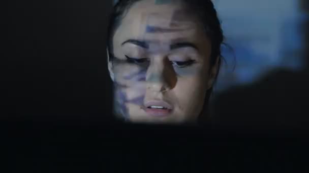 Jeune femme surfant sur les sites Internet assis à l'ordinateur dans une pièce sombre 