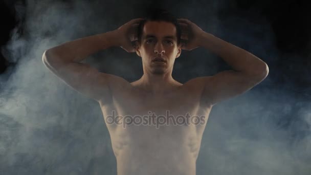 Knappe man van de shirtless en permanent op donkere achtergrond, met rook om hem heen. — Stockvideo