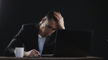 Hüzünlü, yorgun iş adamı ofiste masa başında oturuyor.