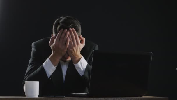 Sad businessman cries while sitting at a desk in office — Stock Video