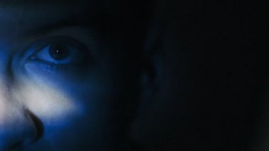 genç adam geceleri bir film izlerken aşırı close-up. Yansıma yüzünde