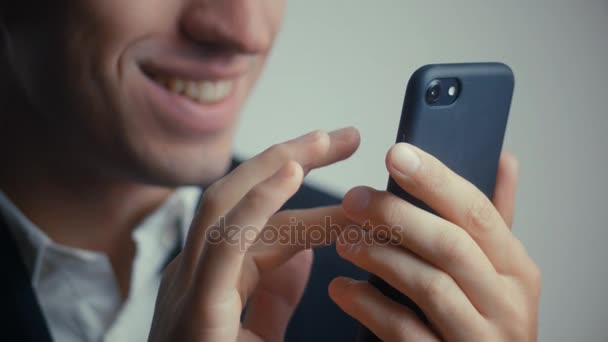 Primo piano di un uomo d'affari felice sorridente in giacca e cravatta sta usando uno smartphone. Isolato su sfondo bianco — Video Stock