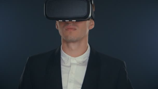 Joven hombre de negocios utiliza gafas de realidad virtual en habitación negra . — Vídeos de Stock