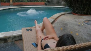 Delikanlı iken onun kız yapıyor ve bir şezlong üzerinde güneşlenme mavi havuzu suya atlama yaz tatilde