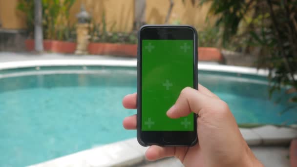 Primer plano de las manos masculinas tocando el teléfono inteligente en las vacaciones cerca de la piscina. Tecla de croma de pantalla verde . — Vídeos de Stock
