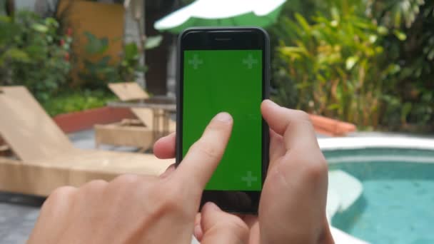 Close-up van het mannelijke handen aanraken van smartphone op vakantie bij zwembad achtergrond. Groen scherm Chroma Key. — Stockvideo