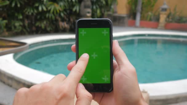 Primo piano di mani maschili che toccano di smartphone all'atto di vacanza vicino alla piscina. Chiave cromatica a schermo verde . — Video Stock