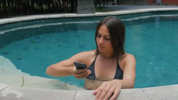 Jovem morena fazendo selfie usando smartphone na piscina em férias — Vídeo de Stock