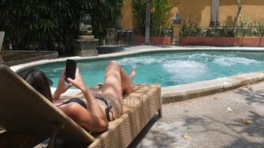 Delikanlı iken onun kız yapıyor ve bir şezlong üzerinde güneşlenme flip mavi havuzu suya atlama yaz tatilde
