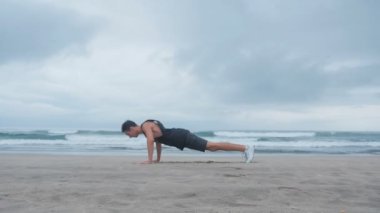 Sahilde bir çapraz-eğitim yapan genç erkek. Adam presler ve arka plan okyanus plaj bir backflip yok