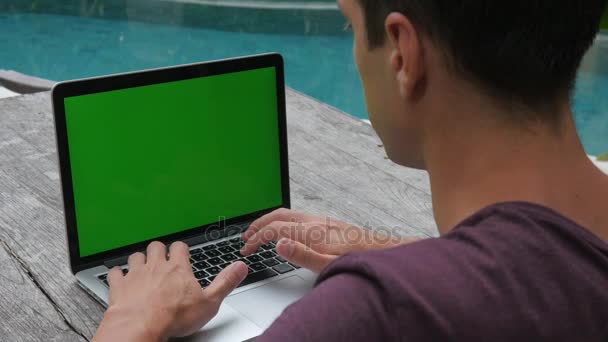 Mann arbeitet am grünen Bildschirm des Laptops. Außen ordentlich am Pool. Arbeit und Reisen — Stockvideo