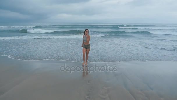 Портрет счастливой молодой женщины, бегущей возле океанских волн — стоковое видео