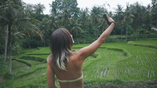 Jeune femme profitant de la nature dans la forêt tropicale verte et faire du selfie avec smartphone — Video