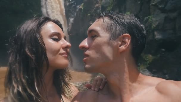 Giovani turisti di famiglia che scattano selfie vicino a una bella cascata nella giungla di Bali. Coppia baci e scatta foto — Video Stock