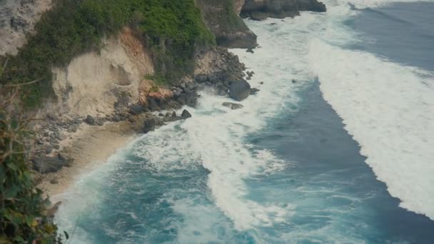 Havets vågor bryta på sten klippor. Översta Flygfoto över tropiska stranden Bali, Indonesien. Slow motion — Stockvideo