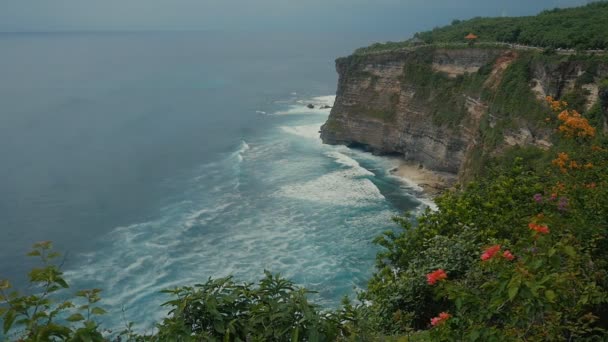 海洋波石の崖の上。インドネシア、バリ島の熱帯のビーチの空中の平面図です。スローモーション — ストック動画