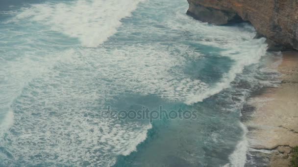 Oceánu vlny tříštící se o kamenné útesy. Letecký pohled shora tropické pláže Bali, Indonésie. Zpomalený pohyb — Stock video