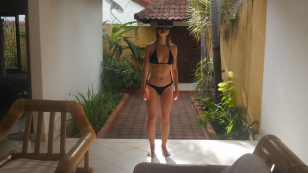 Mujer joven en bikini utiliza unas gafas de realidad virtual en casa en verano — Vídeo de stock