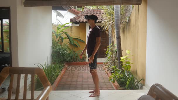 Jonge man maakt gebruik van een virtual reality-bril thuis — Stockvideo
